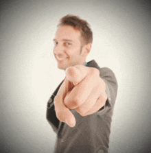 a man in a suit points at the camera