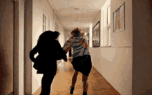 a couple of people are running down a hallway together