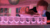 a bartender pouring a drink into shot glasses