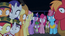 a group of ponies are standing in a line with one wearing a green hat with a gold emblem