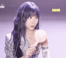 a girl with purple hair is holding a fan in her hand .
