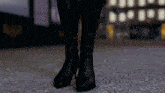 a woman wearing a pair of black boots standing on a carpet