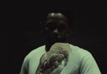 a man in a white shirt holds an owl in his hands
