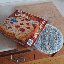 a box of pizza giuseppe sits on a wooden counter