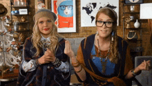 two women sitting next to each other with a map of the world on the wall behind them