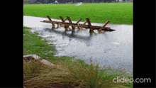 a flooded field with a wooden fence in the foreground and clideo.com in the bottom right corner