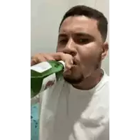 a man is drinking from a green bottle with a straw in his mouth .