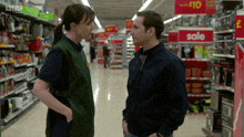 a man and a woman are talking in a store with a sign that says sale