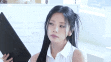 a woman with long black hair is holding a clipboard in her hand .