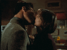 a man and a woman are kissing in a kitchen