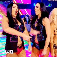 a couple of women are standing next to each other in a room with a rainbow background .