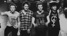 a group of young men are posing for a picture and one of them is wearing a peace sign tank top