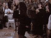 a woman in a black dress is dancing in front of a crowd