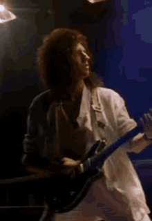a man in a white shirt is playing a guitar on a stage .