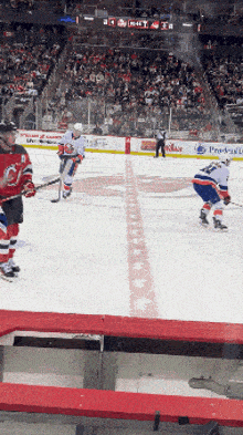 a hockey game is being played in front of a crowd with a banner for prudential in the background