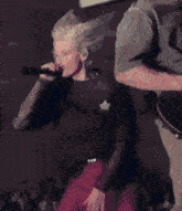 a person singing into a microphone with their hair in the air
