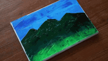 a person is painting a picture of a mountain with green and blue colors