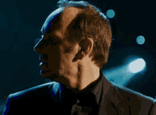 a man in a suit and tie is standing in front of blue lights