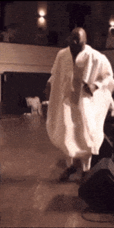 a man in a white robe is dancing on a wooden floor