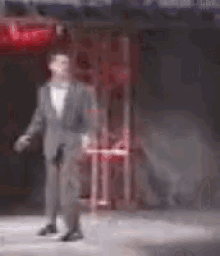 a blurry picture of a man in a suit standing in front of a red sign .