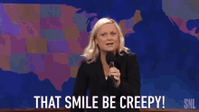 a woman speaking into a microphone with the words that smile be creepy behind her
