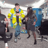 a man in a yellow jacket is dancing with another man in a black shirt in a room .