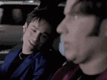 a man in a blue jacket is talking to another man in a car