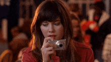 a woman in a red jacket is taking a picture with a canon camera