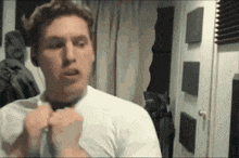 a man in a white shirt is making a funny face while adjusting his tie .