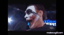 a man with a clown face painted on his face is on a television screen .