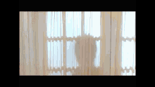 a person standing in front of a window with white curtains on it