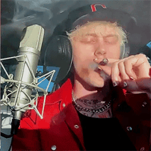 a man is smoking a cigarette in front of a microphone and wearing headphones