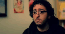 a man with glasses and a beard looks at the camera