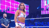 a woman is standing in a wrestling ring while a referee watches .