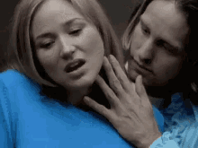 a man is touching a woman 's neck in a blue shirt .