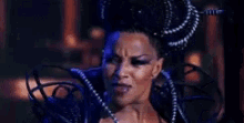 a woman is wearing a purple wig and a blue crown .