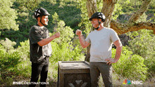 two men giving each other a fist bump in front of a box that says nbc destination x