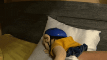 a stuffed toy with a blue helmet on laying on a bed