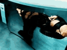 a woman in black lingerie is laying on her back on a table