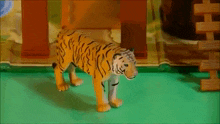 a toy tiger is standing on a green table