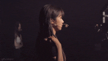 a woman with a microphone in her mouth is standing in the dark