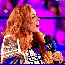 a woman with red hair is holding a wrestling championship belt and speaking into a microphone with a w logo on it