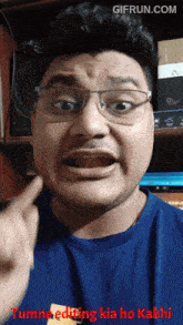 a man wearing glasses and a blue shirt is making a funny face