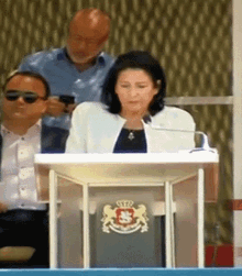 a woman sitting at a podium with a lion on it