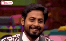 a man with a beard is smiling and wearing a suit .