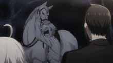 a man is hugging a white horse while another man watches