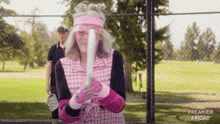 a woman is holding a baseball bat in front of a fence with freakier friday written on it