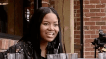a woman with a nose ring is sitting at a table with glasses of water and a straw .