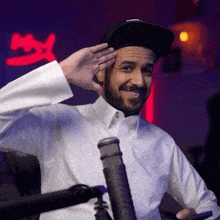 a man wearing a white shirt and a black hat salutes