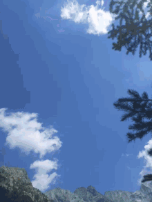looking up at a blue sky with clouds and mountains